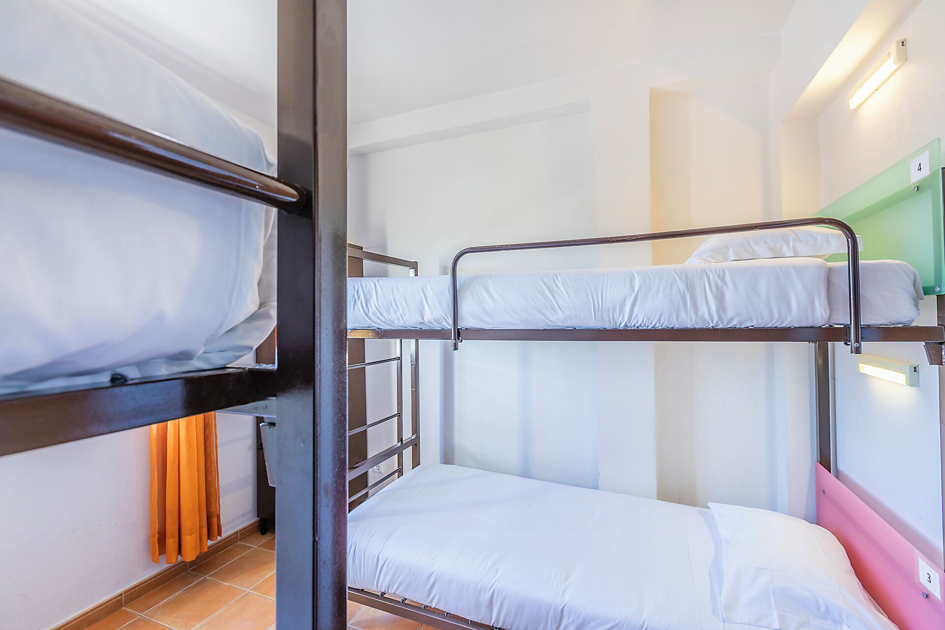 A bunk bed room with a ladder, a single bed, and a green wall.