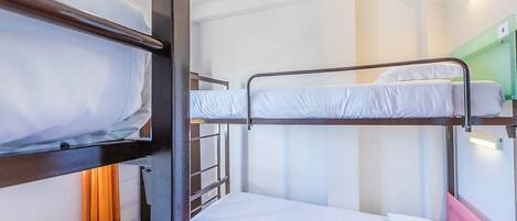 A bunk bed room with a ladder, a single bed, and a green wall.