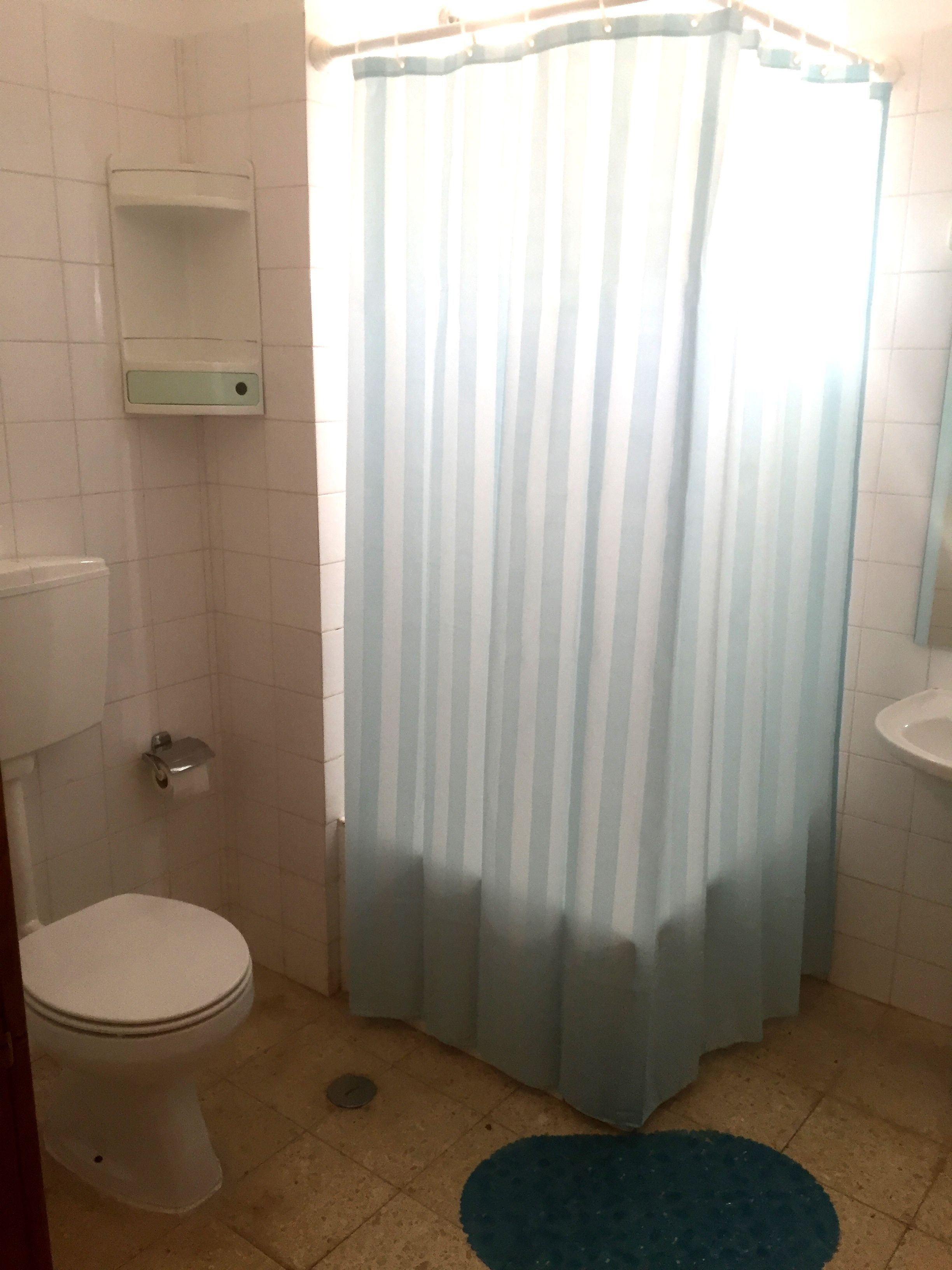 Un baño con inodoro, lavabo y cortina de ducha.