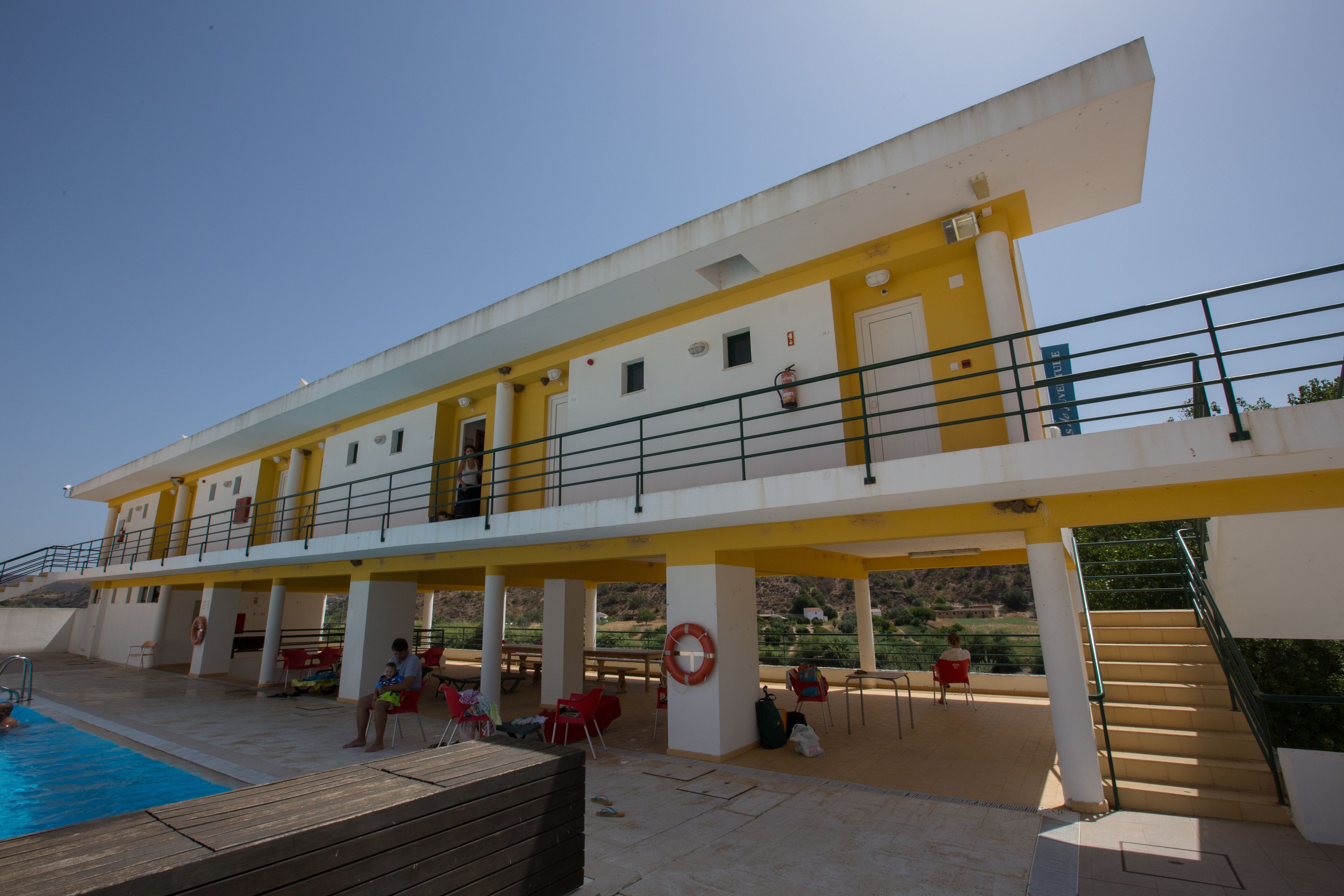 Een buitenzwembad, ligstoelen bij het zwembad