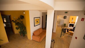 A spacious living area with a sofa, a potted plant, and a framed picture on the wall. - HI Alcoutim – Pousada de Juventude - Hostel (Alcoutim)