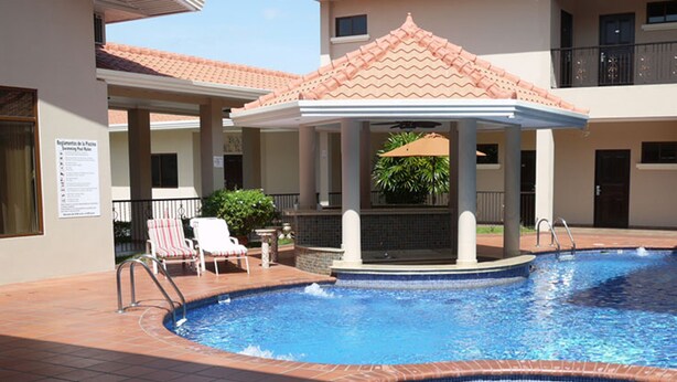 Ein Swimmingpool mit Gazebo, Liegestühlen und einer gefliesten Terrassenfläche.