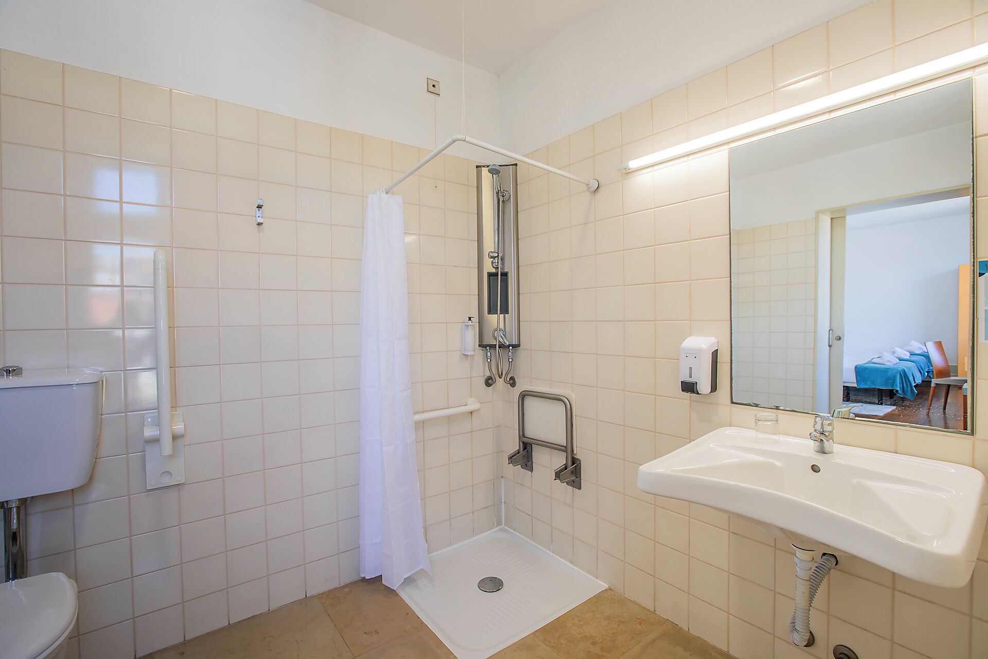 A bathroom with a shower, toilet, sink, and a mirror.
