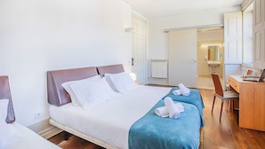 Hotelkamer met een bed, bureau, stoel en badkamer, zichtbaar door een geopende deur.