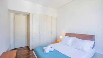 Una habitación de hotel con una cama, un banco de madera y un armario.
