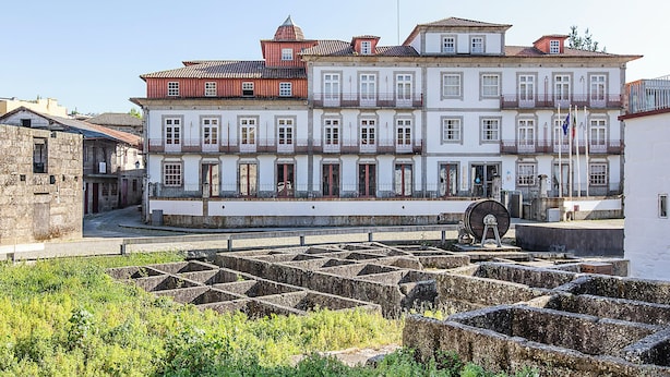 Een historisch gebouw met meerdere verdiepingen, een binnenplaats en een doolhofachtige constructie op de voorgrond.