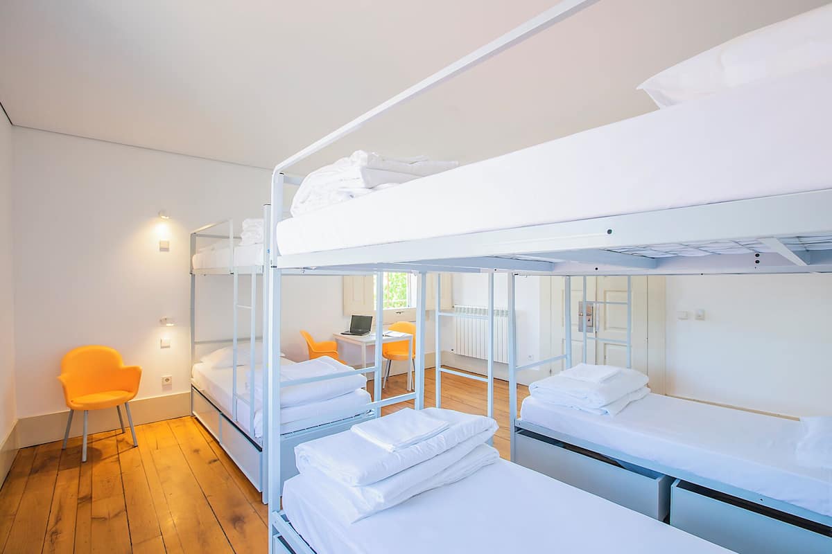 Habitación con literas, escritorio, silla, ventana y radiador.