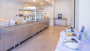 Een moderne keuken met roestvrijstalen apparatuur, een buffet met diverse gerechten en een koffiehoek.