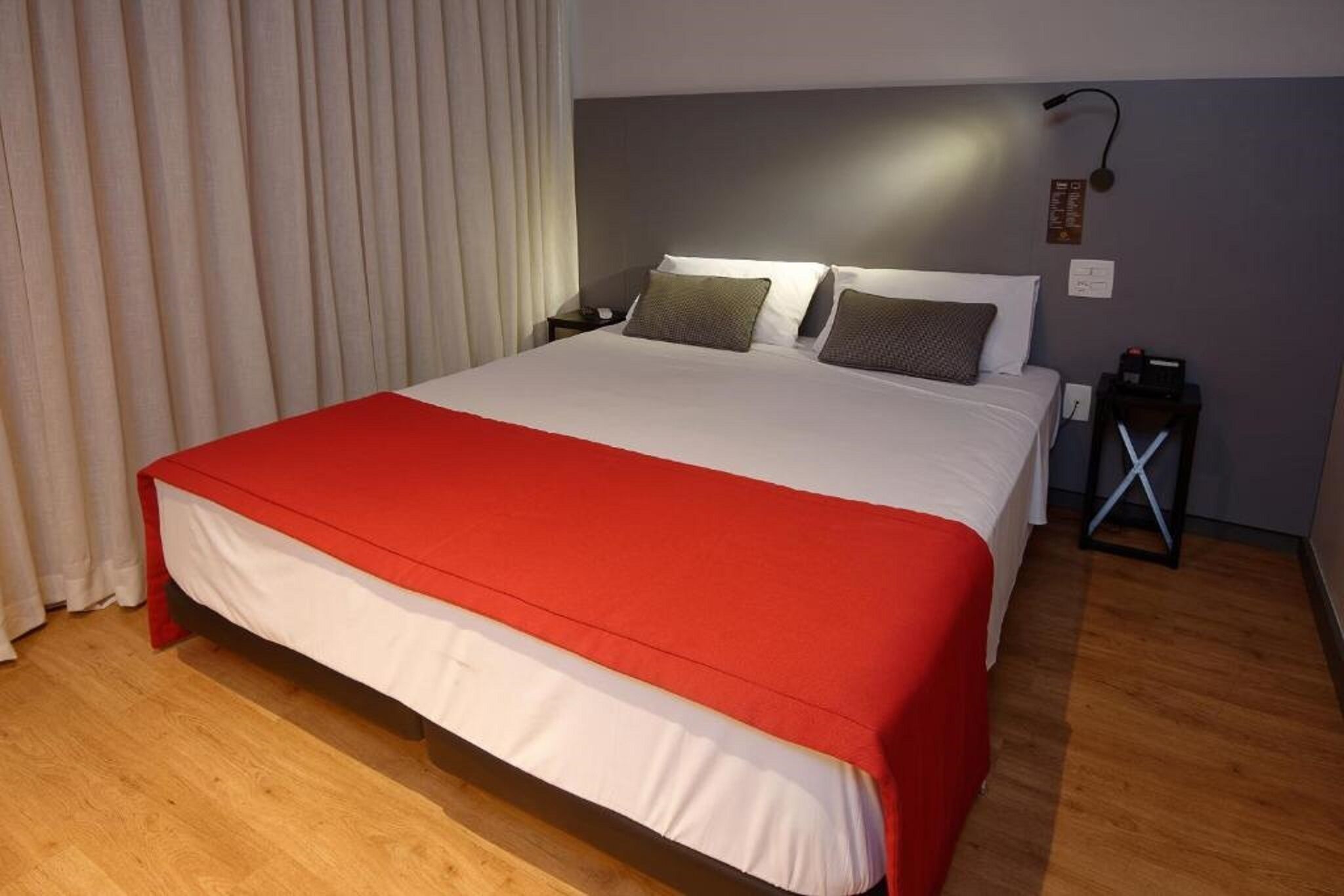 Une chambre d’hôtel avec un grand lit, une table de chevet et une lampe.