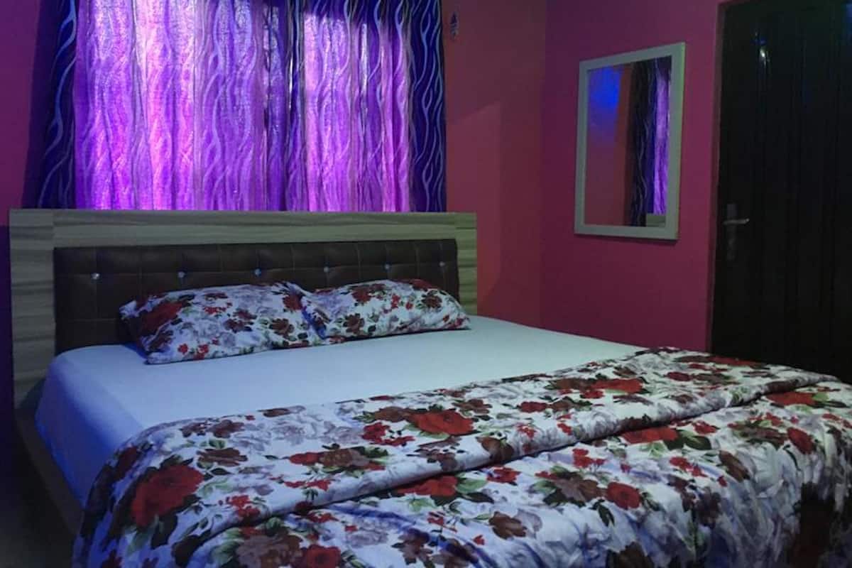 A bedroom with a bed, a headboard, a mirror, and curtains.