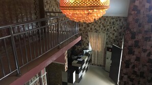 A staircase leading to a balcony with a patterned wall and a hanging chandelier. - Marble Hill Hotel (Lagos)