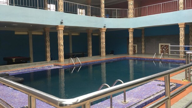 A multi-level indoor swimming pool with a tiled floor and metal railings. - Marble Hill Hotel (Lagos)
