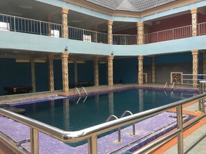 A multi-level indoor swimming pool with a tiled floor and metal railings. - Marble Hill Hotel (Lagos)