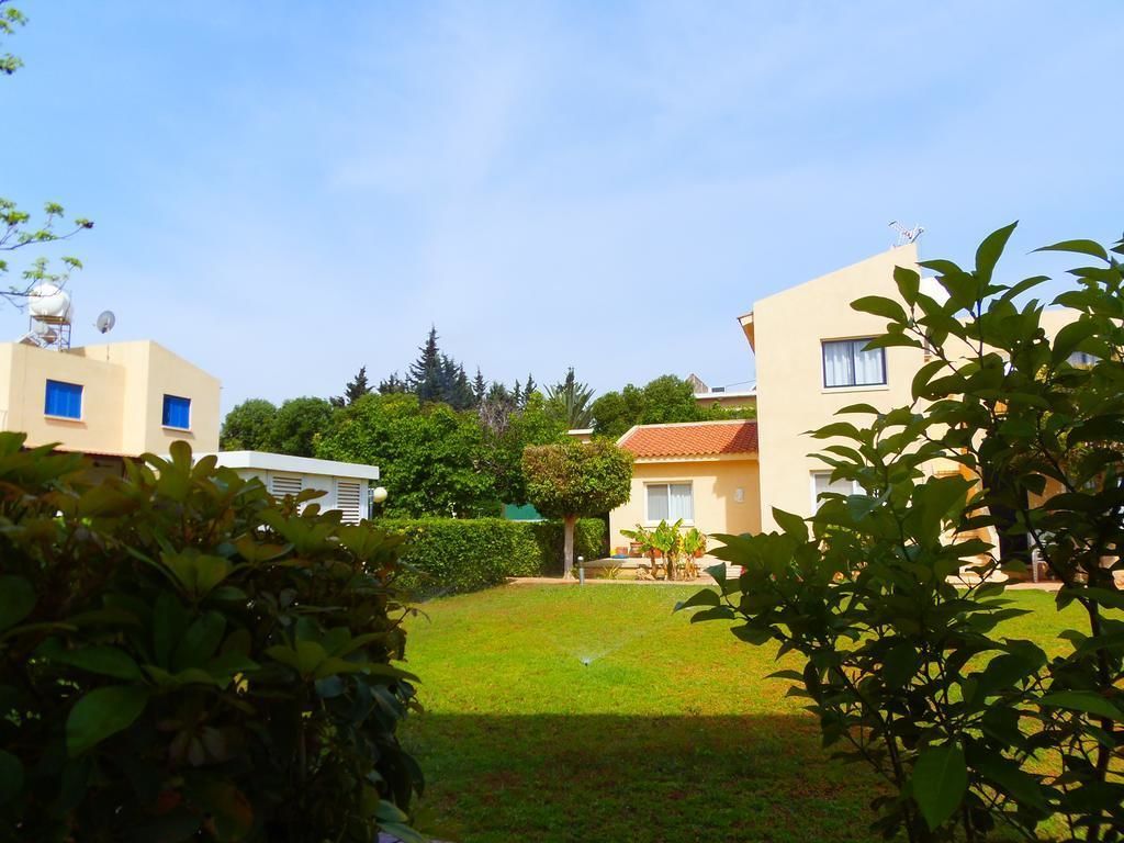 A residential area with two buildings, a well-maintained lawn, and surrounding greenery.