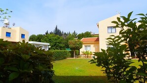 Zona residencial con dos edificios, césped cuidado y vegetación circundante.