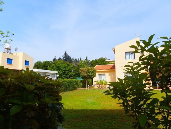 A residential area with two buildings, a well-maintained lawn, and surrounding greenery.