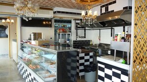 A kitchen with checkered black and white tiles, a glass display case with pastries, and a chandelier. - Fairytale Hotel (Istanbul)