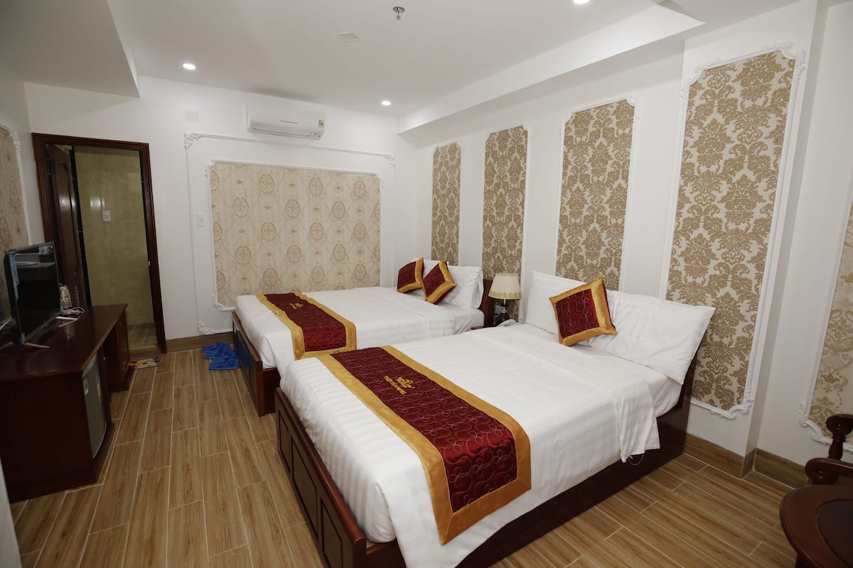 A hotel room with two beds, a desk, and a television.