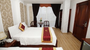 A hotel room with two beds, a small table with chairs, a desk, and a door. - Orange Quy Nhon (Quy Nhon Nam)