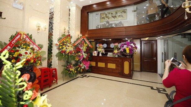 A lobby with a reception desk, floral arrangements, and a staircase. - Orange Quy Nhon (Quy Nhon Nam)