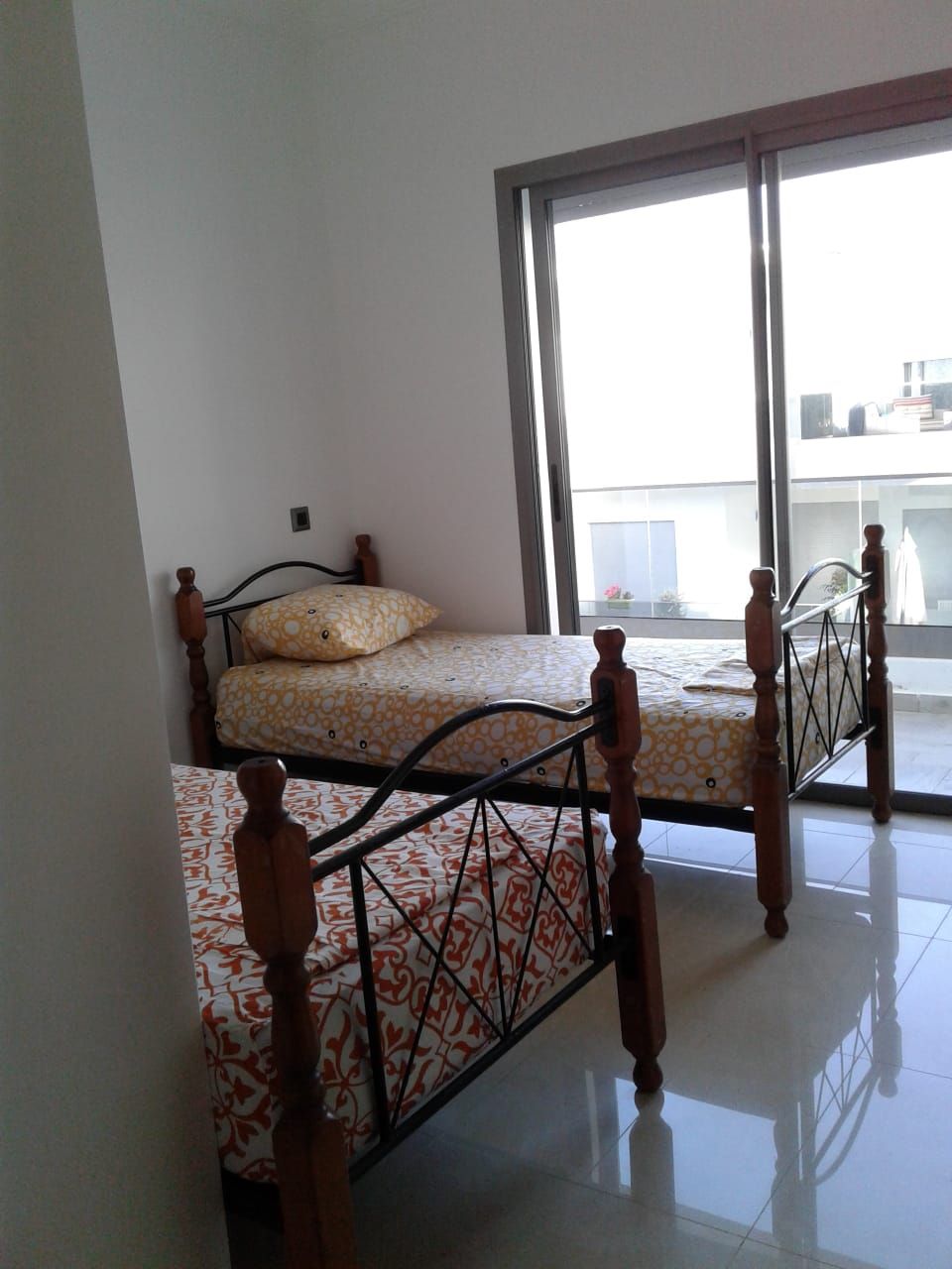 A room with a bed, a window, and a view of the outside.
