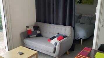 A cozy living room with a grey sofa, a small table, and a colorful striped tablecloth.