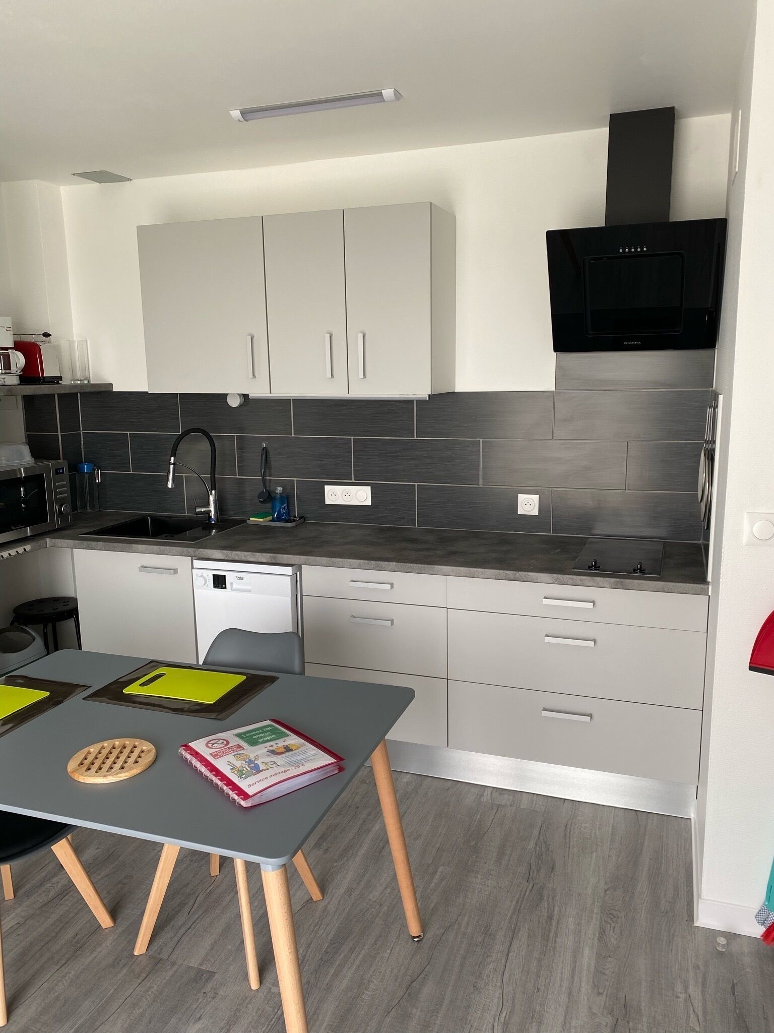 A modern kitchen with white cabinets, a black microwave, and a grey countertop.