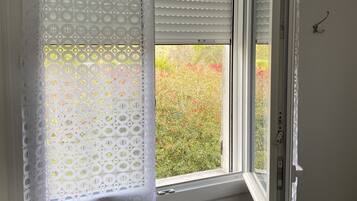 A window with a white curtain and a partially open white blind.