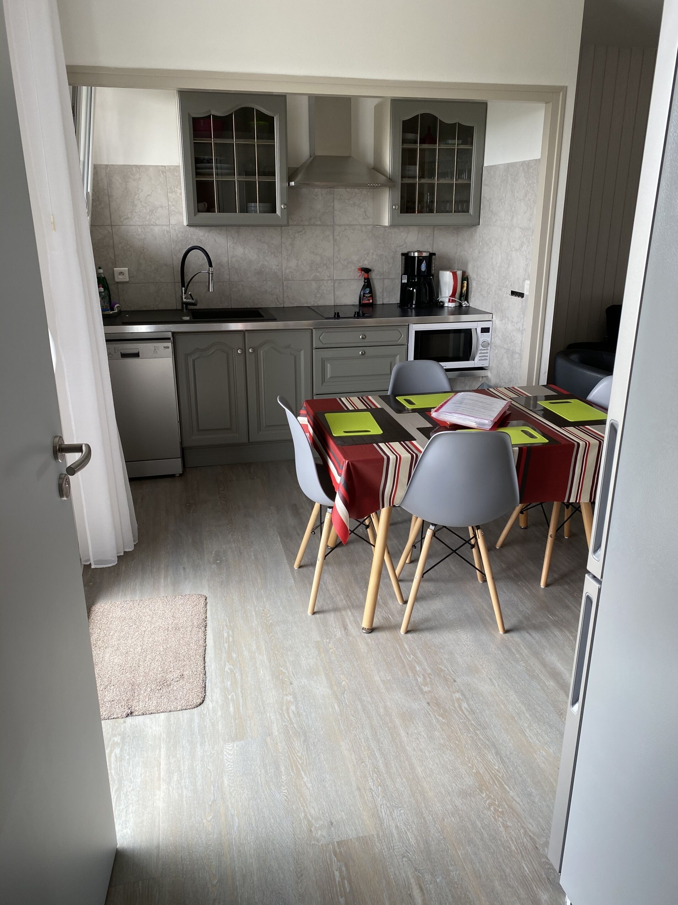 A compact kitchen with a dining area, featuring a microwave, coffee maker, and a dishwasher.