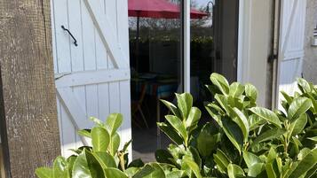 A sliding glass door leading to an outdoor seating area with a red umbrella.