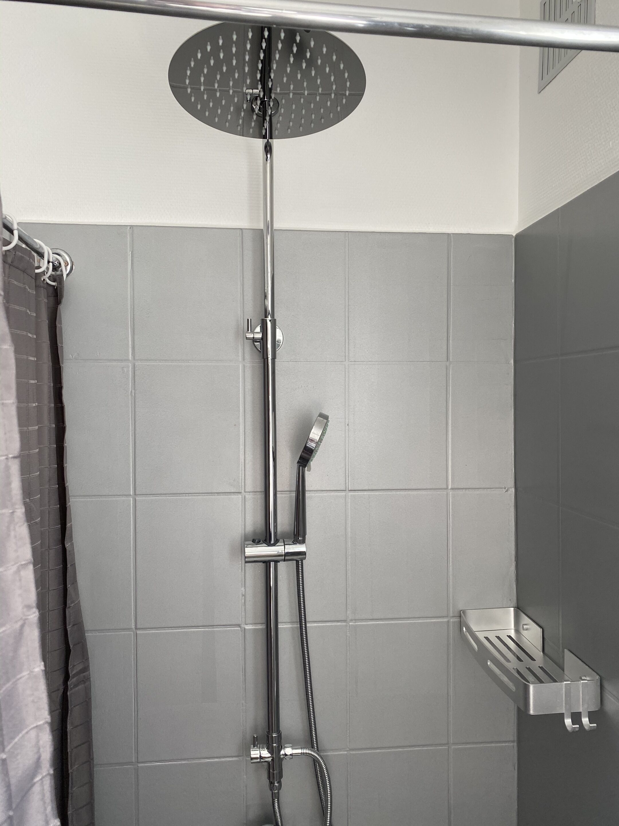 A shower with a handheld showerhead and a rain shower head, a towel rack, and a soap dish.