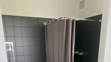 A bathroom with a toilet, a shower with a grab bar, and a towel rack.