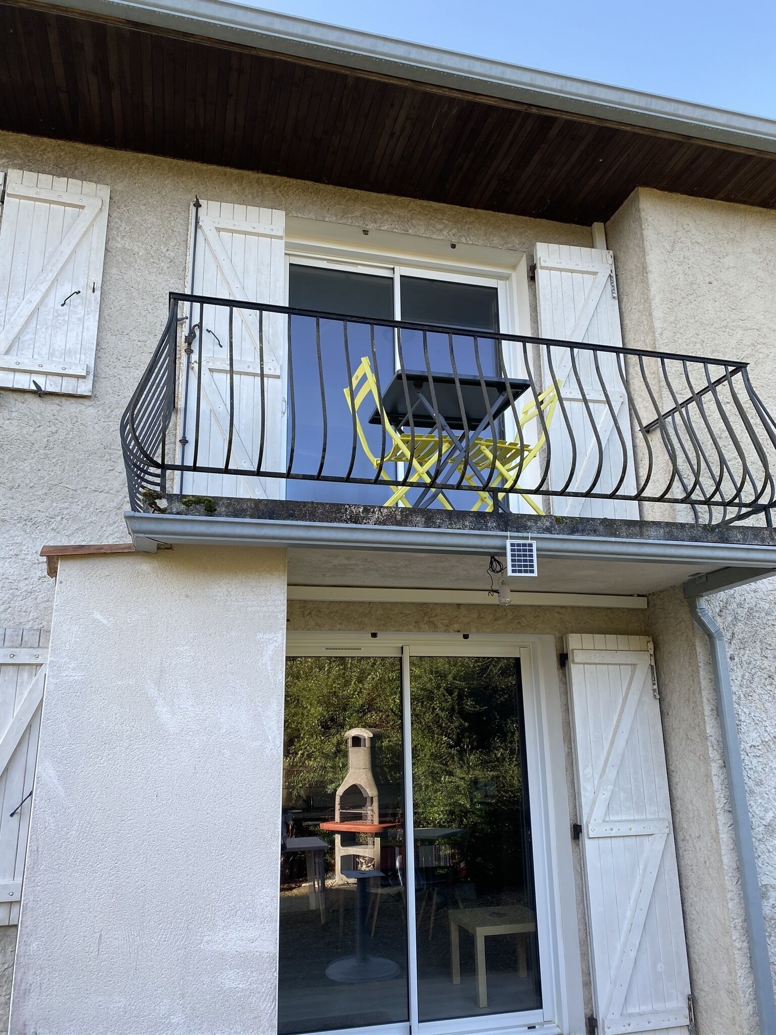 Un bâtiment doté d’un balcon avec une rambarde en métal noir et une chaise jaune.