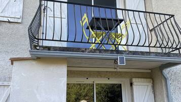 Un bâtiment doté d’un balcon avec une rambarde en métal noir et une chaise jaune.