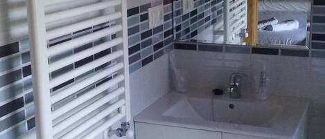 Un baño con lavabo blanco, un espejo y un perchero para toallas.