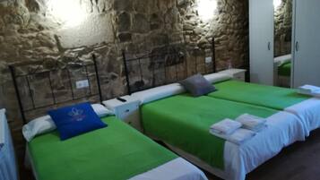 A room with two beds, stone walls, and a wardrobe.