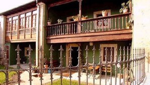 A traditional building with a balcony, a wrought iron fence, and potted plants. - Casa Florentina (Cabrales)