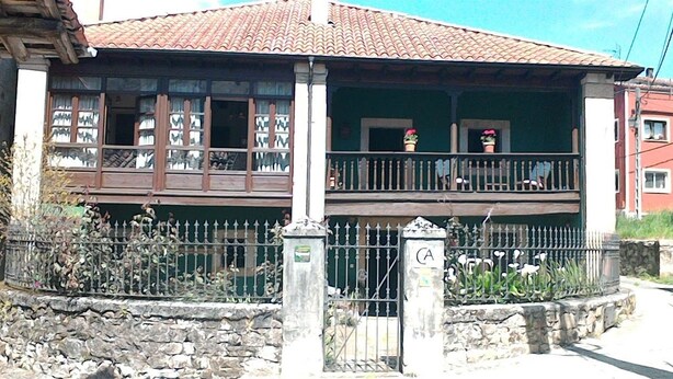 A traditional building with a balcony, stone wall, and a metal gate. - Casa Florentina (Cabrales)