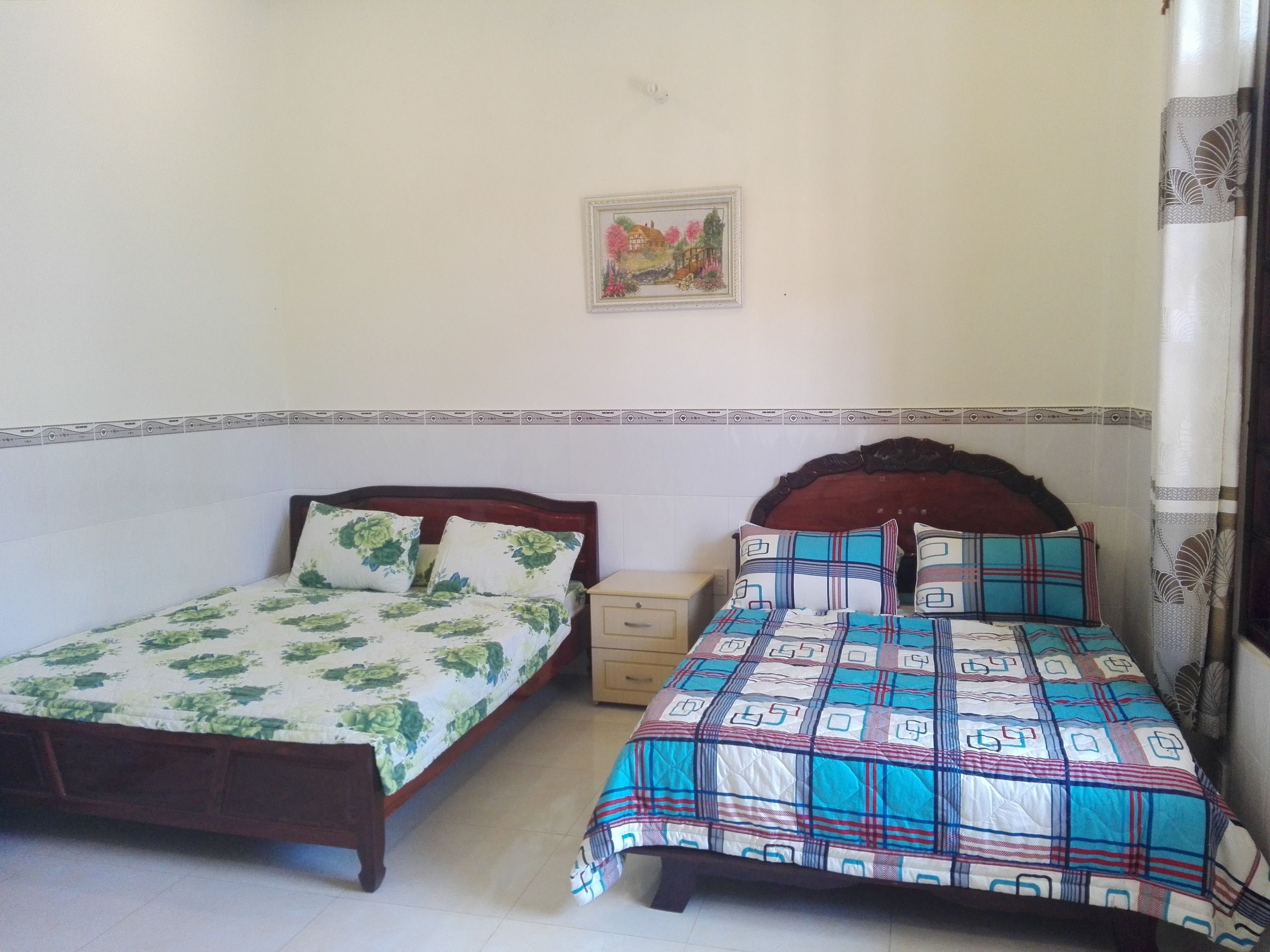 A bedroom with two single beds, a nightstand, a small cabinet, and a framed picture on the wall.