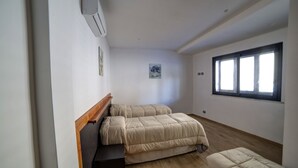 Un dormitorio con dos camas, cabecero de madera, una ventana pequeña y aire acondicionado instalado en la pared.