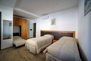 A hotel room with three beds, wooden wardrobe, and a painting on the wall. - Bed and Breakfast Controtempo (Reggio Calabria)