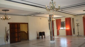 Un hall d’entrée spacieux, agrémenté d’un lustre, d’une porte en bois, d’une petite table et d’un miroir.