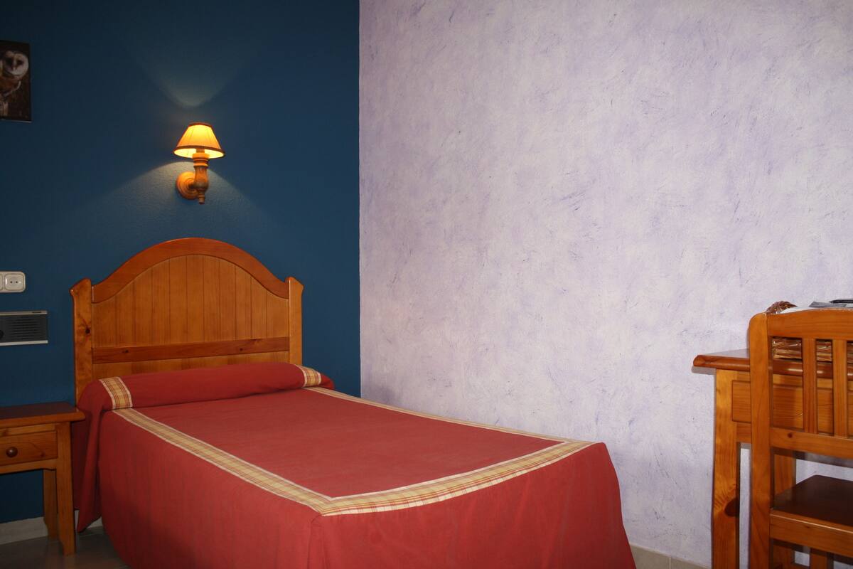 Une chambre à coucher avec un lit en bois, une table de chevet, une lampe et une chaise.
