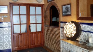 Un intérieur traditionnel avec une porte en bois, un sol carrelé et une applique murale décorative.