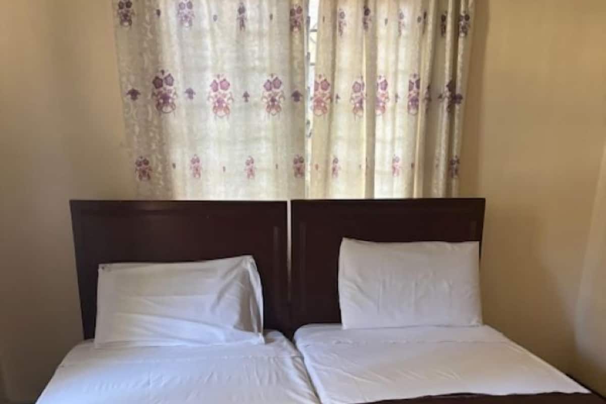 A double bed with a wooden headboard, white bedding, and a brown throw blanket.