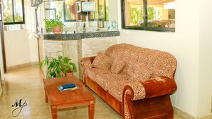 Ein Wohnzimmer mit einer Couch, einem Couchtisch und einer Zimmerpflanze.
