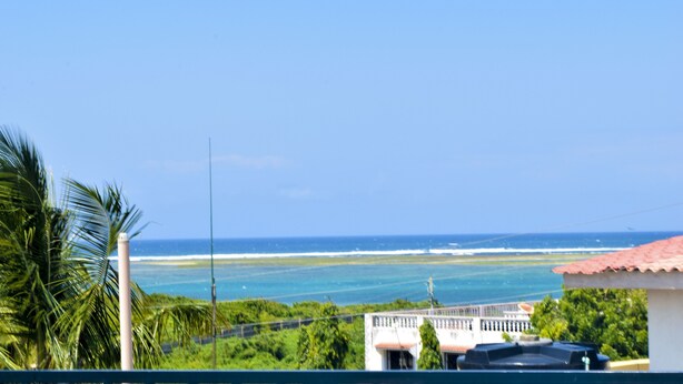 Blick auf die Küste mit blauem Himmel, einem Strand und einem Gebäude mit rotem Dach.