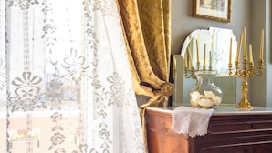 A room with a wooden dresser, a bed with a patterned bedspread, a lace window treatment, and a framed picture on the wall. - Casa Isabella (Rocca San Giovanni)