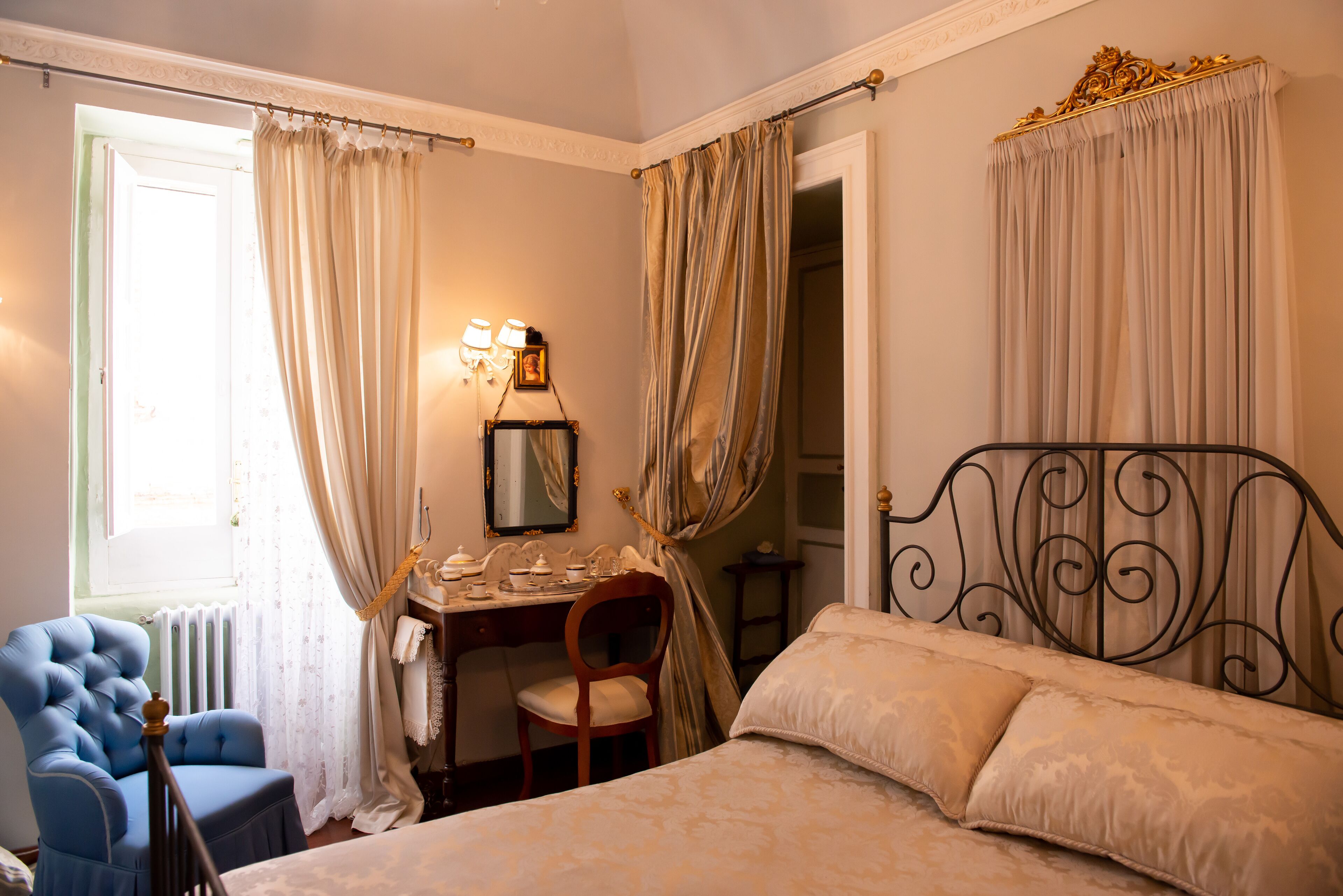A bedroom with a bed, a desk, a chair, and curtains.
