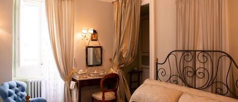 A bedroom with a bed, a desk, a chair, and curtains.